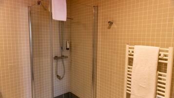 Une douche fermée par des parois de verre, avec une serviette blanche accrochée au mur.