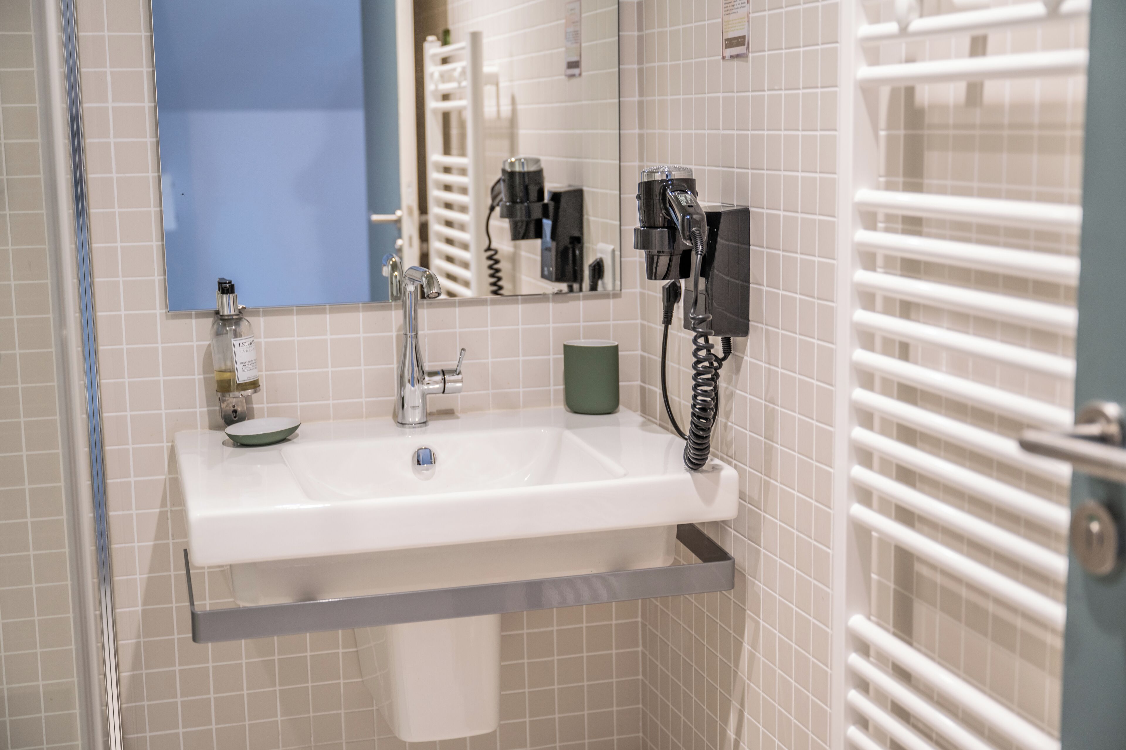 A bathroom with a white sink, a mirror, a towel rack, and a hairdryer.