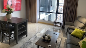 A modern living room with a large window, a dining area, and a sofa. - Luxurious 1 Bedroom King Bed Skyline View Walking Street Condo (Angeles)