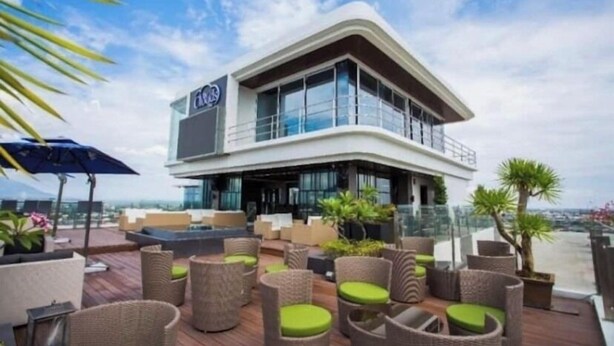 A modern building with a balcony area featuring wicker furniture and potted plants. - Luxurious 1 Bedroom King Bed Skyline View Walking Street Condo (Angeles)