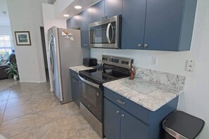 A compact kitchen with a refrigerator, microwave, stove, and a small countertop.