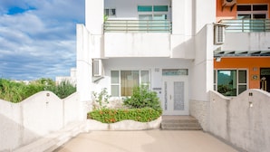 A modern building with a gated entrance, a small garden with red flowers, and a clear sky. - Pet Friendly Taitung Chun Yang Smart Stay (Taitung)