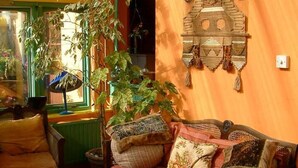 Een gezellige woonkamer met een bank, een fauteuil, een grote plant en een decoratief object aan de muur.