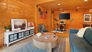 Una camera accogliente in stile chalet, con pareti in legno, televisione, zona pranzo e divano.