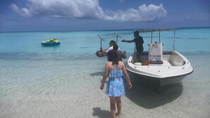 Un barco amarrado en una playa con agua turquesa cristalina y una orilla arenosa.