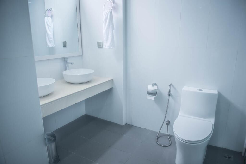 Et moderne badeværelse med hvid vask, spejl og toilet.