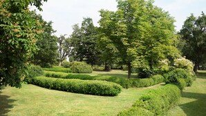A well-maintained garden with neatly trimmed hedges and mature trees. - Uckermark-Im Gutshaus vacation apartment (Boitzenburger Land)