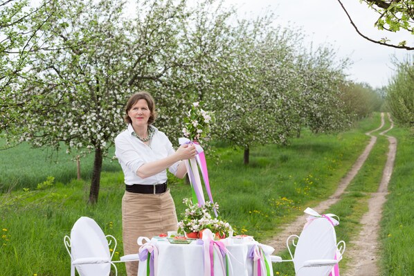 A woman arranging a table with a bouquet of flowers and a ribbon.