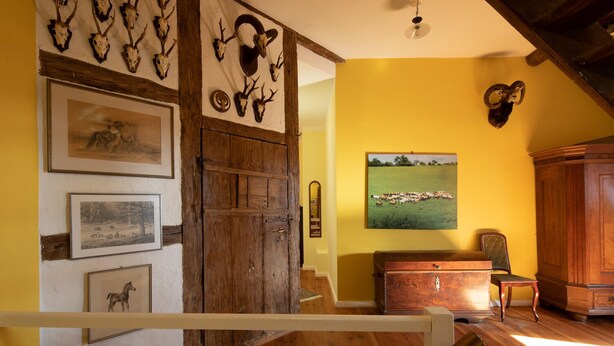 A rustic interior with wooden walls, a large wooden door, and a staircase leading to a loft. - Uckermark-Im Gutshaus vacation apartment (Boitzenburger Land)