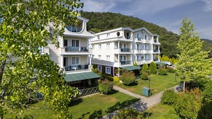 Ein mehrstöckiges Hotel mit Balkonen, umgeben von üppiger Vegetation und einer Bergkulisse.