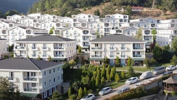 Stunning apartment buildings with balconies and flat roofs, set amidst lush greenery and surrounded by hills.
