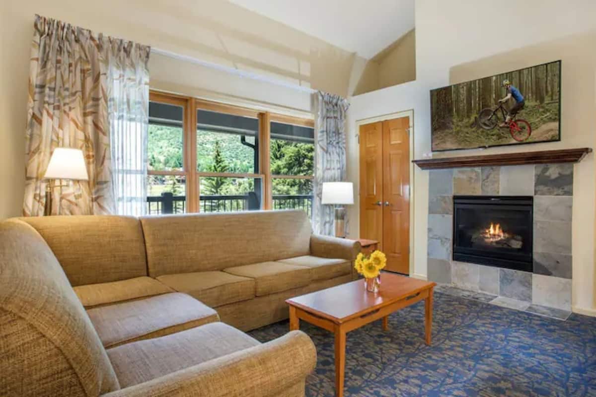 A living room with a sofa, a coffee table with flowers, a fireplace, and a painting of a mountain biker.
