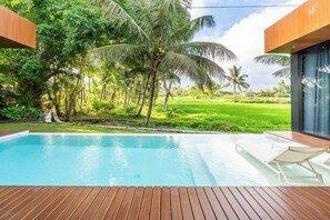 Una piscina con cubierta de madera, rodeada de exuberante vegetación y palmeras.
