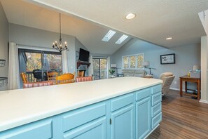 A spacious kitchen with a large island, a chandelier, and a view of the outdoors.