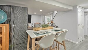 A dining area with a white table, two white chairs, and a wooden sideboard. - Saddle Brook Studio with Patio - Near NYC! (Saddle Brook)