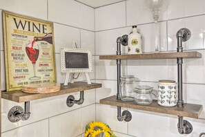 A kitchen with white tiled walls, wooden shelves, and a wine-themed poster. - Saddle Brook Studio with Patio - Near NYC! (Saddle Brook)