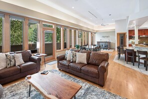 A spacious living room with leather sofas, a wooden coffee table, and large windows offering a view of the outdoors. - Penthouse Condo w/ Grand Views | Walk to Lionshead | 2 Masters & Decks (Vail)