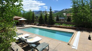A swimming pool with lounge chairs and a stone patio.