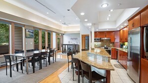 A modern kitchen with a large island, wooden cabinets, and stainless steel appliances.