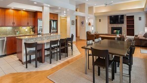 A modern kitchen with granite countertops, dark wooden cabinets, and a built-in refrigerator.