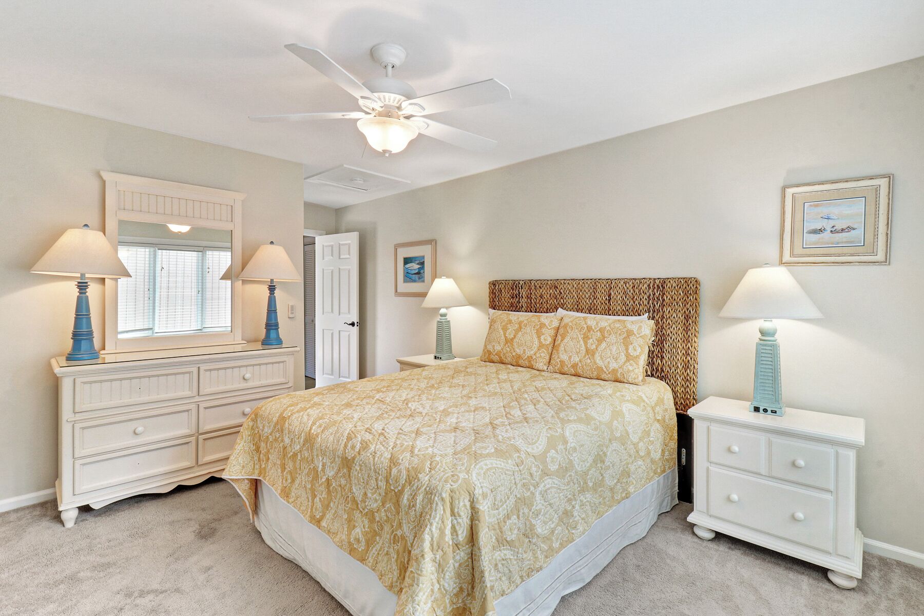 A bedroom with a bed, two nightstands, a dresser, a ceiling fan, and a window with blinds.