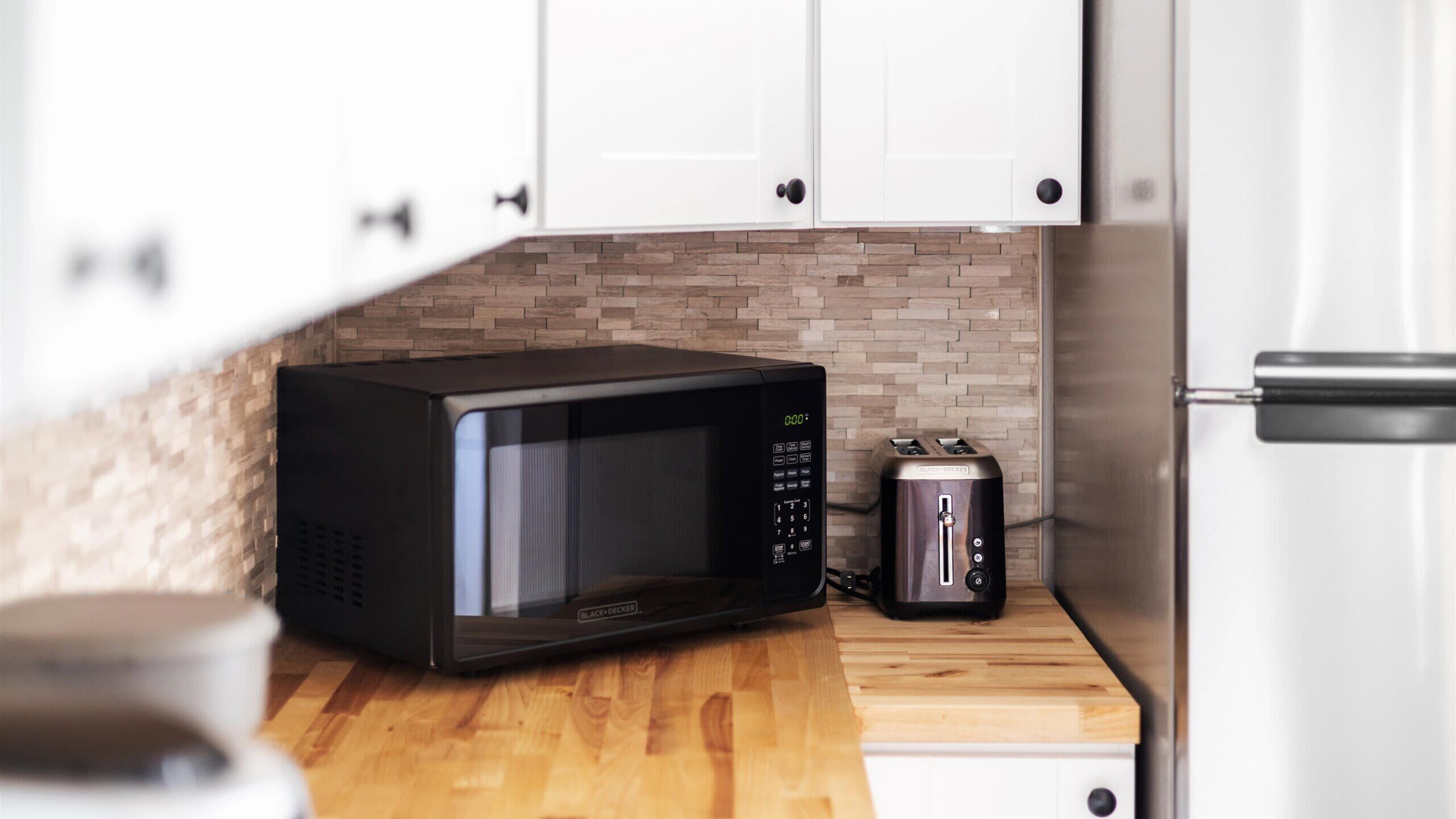 A kitchen with a microwave, toaster, and a white refrigerator.