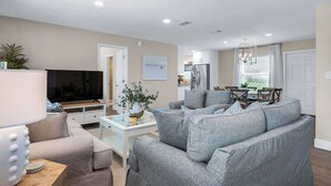 Una sala de estar moderna con un sofá gris, un televisor de pantalla plana y una mesa de centro de vidrio.
