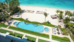 Un resort con una amplia piscina, playa y palmeras.