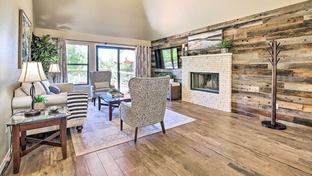 Una sala de estar con chimenea, piso de madera y vistas al exterior.
