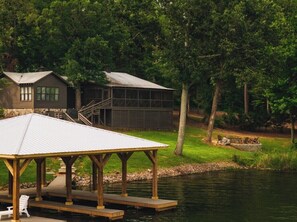 A lakeside cabin with a dock, a covered seating area, and a staircase leading to an upper level. - Chalet Premiere at Signal Point (Guntersville)