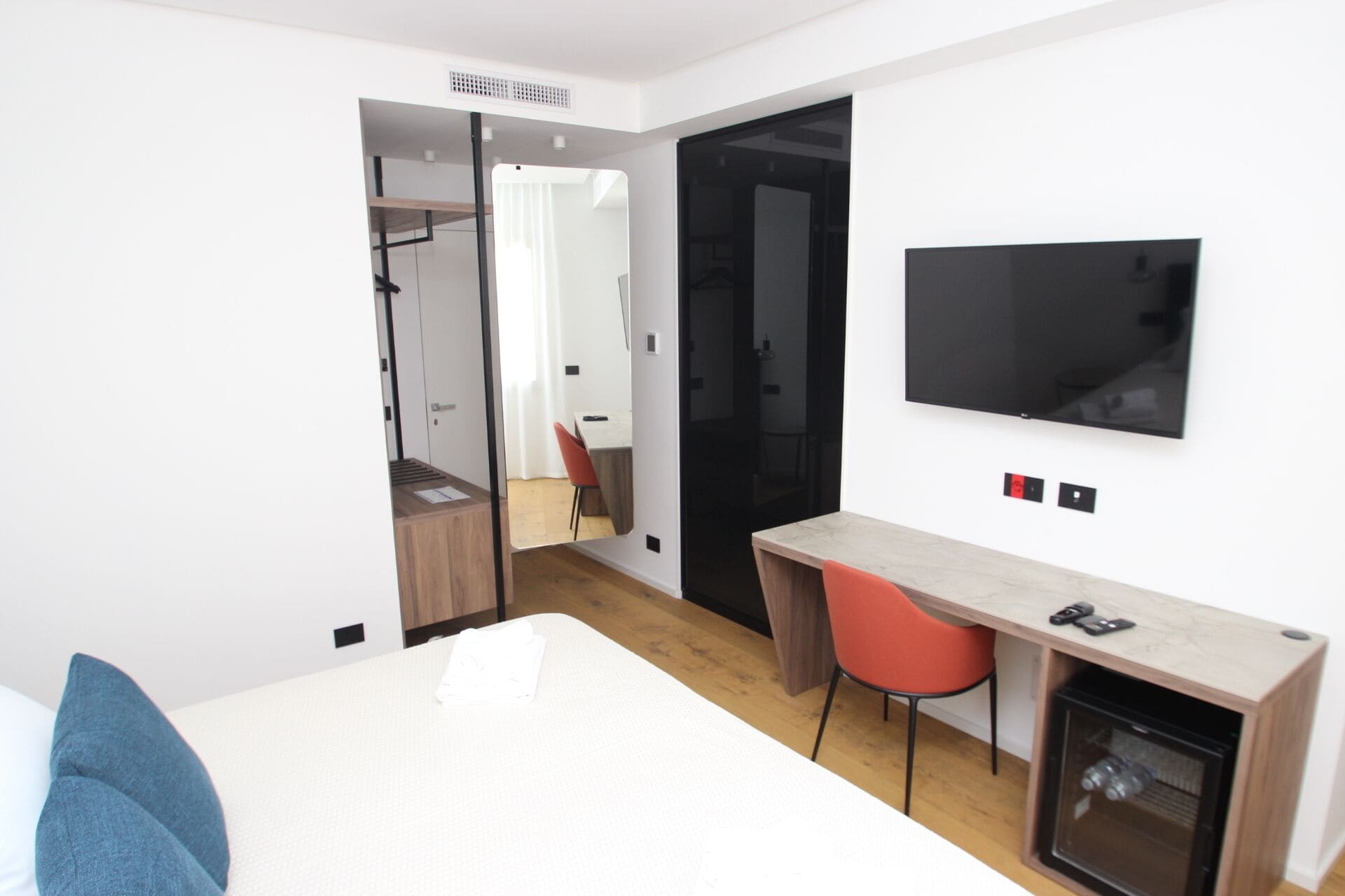 Une chambre d’hôtel moderne équipée d’un lit, d’un bureau, d’une chaise, d’une télévision et d’une armoire.