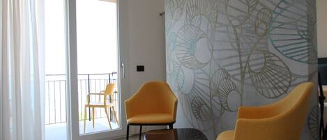 A modern living room with two yellow chairs, a small table, and a large abstract wall mural.