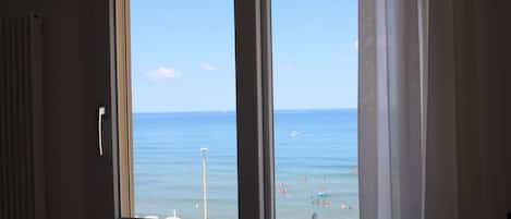 A room with a large window overlooking a beach.