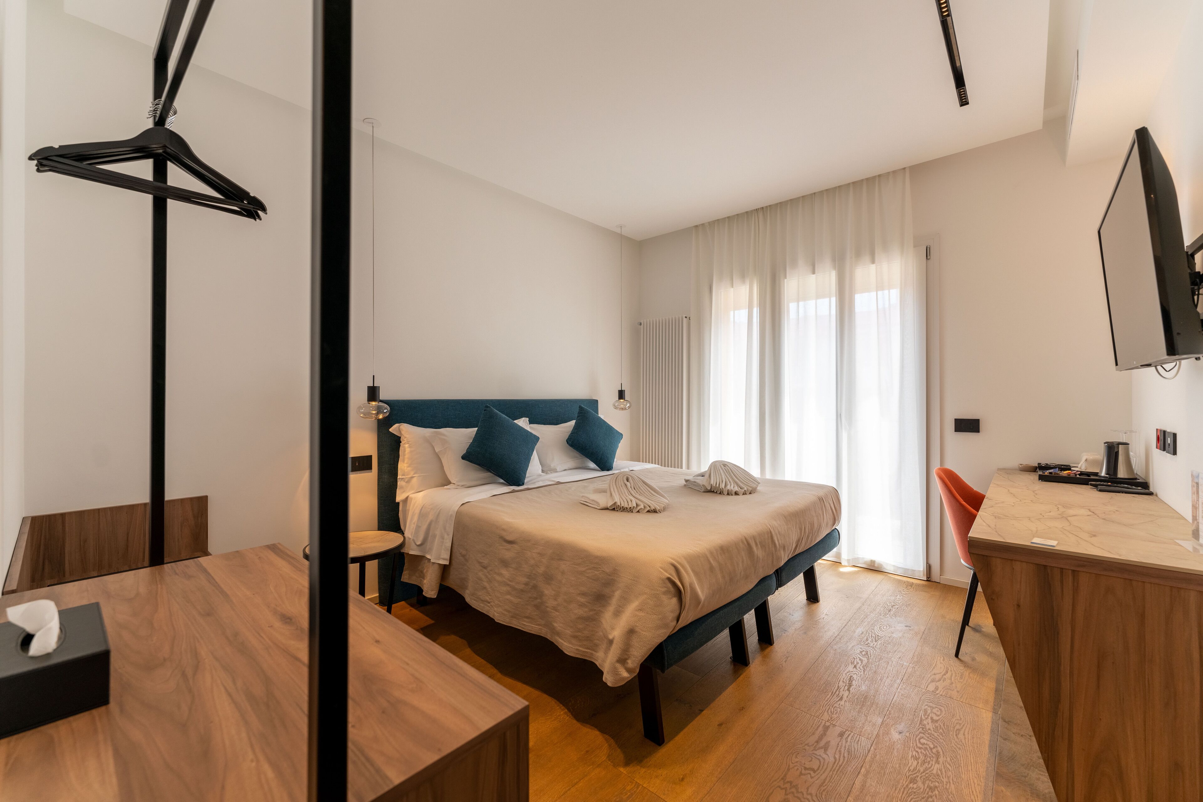 A modern hotel room with a bed, a desk, and a TV.