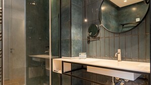 Un baño moderno con cabina de ducha de vidrio, un lavabo blanco y un espejo.