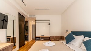 Una habitación de hotel moderna con una cama grande, un escritorio, un espejo y una puerta corredera que da al baño.