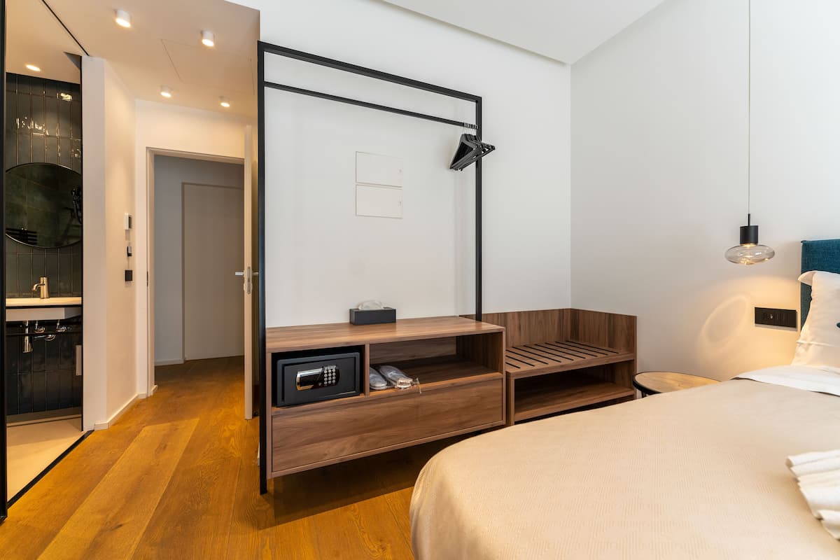 A modern hotel room with a wooden bed, a built-in desk, a microwave, and a small seating area.