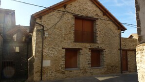 Ein Steinhaus mit zwei Holzläden, einer Metalttür und einem kleinen Fenster.
