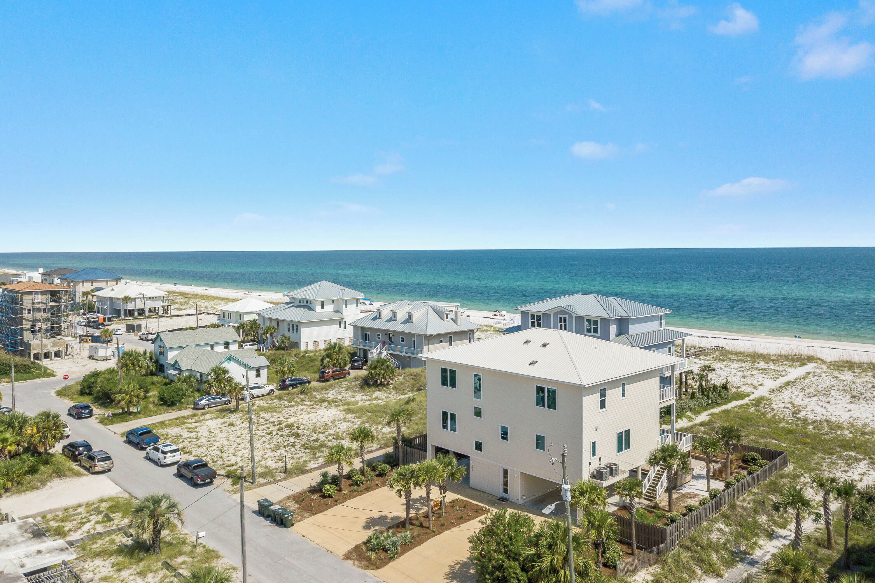 A coastal residential area with multiple two-story houses, a sandy beach, and a clear blue sky.