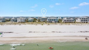 A beachfront property with multiple houses, a sandy beach, and a clear view of the ocean.