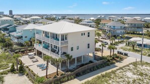 A beachfront property with multiple levels, balconies, and a view of the ocean.