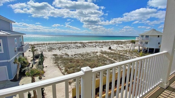 A beachfront property with a balcony overlooking the beach and ocean.