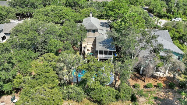 Una casa grande rodeada de árboles frondosos, con piscina visible y vista al océano.