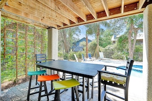 An outdoor patio with a wooden pergola, a pool, and a view of a house.