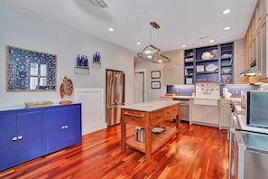 A modern kitchen with wooden flooring, a central island, and blue cabinetry.
