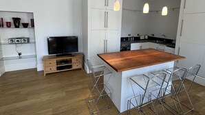 A modern kitchen with white cabinets, a wooden island, and bar stools. - Central 1-bed Apartment in Inverness, Sleeps 4 (Inverness)