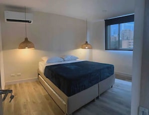 Relax in this serene bedroom with a single bed, pendant lights, and a city view.