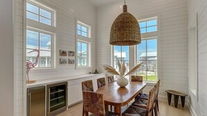 A dining area with a wooden table, wicker chairs, and a hanging light fixture.