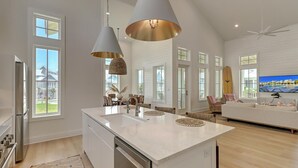 A spacious kitchen with a large island, pendant lights, and a view of the outside.