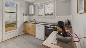 Ett kompakt kök med diskmaskin, ugn och vattenkokare på bänkskivan.